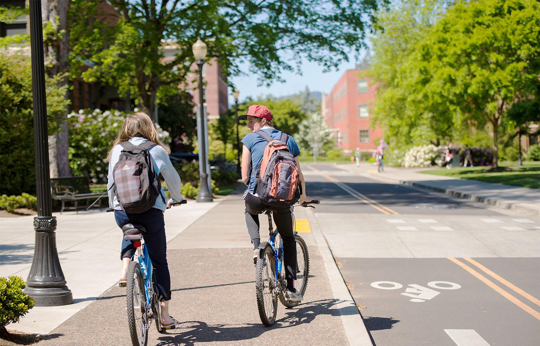 Two students biking on campus.