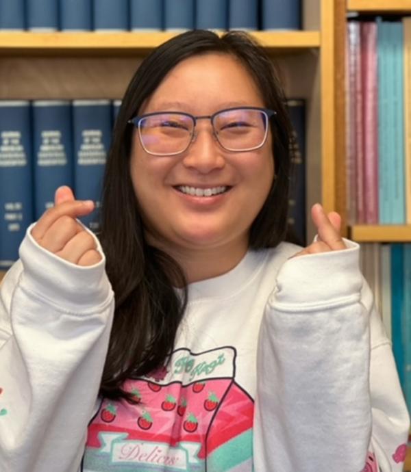 Headshot of a smiling, happy statistics student standing in front of a bookcase