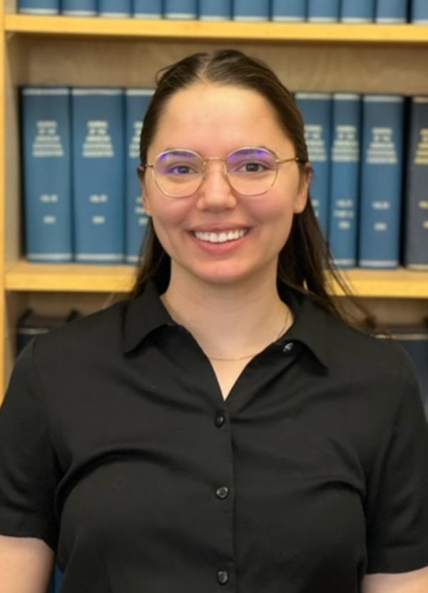 Smiling student standing in front of a bookshelf