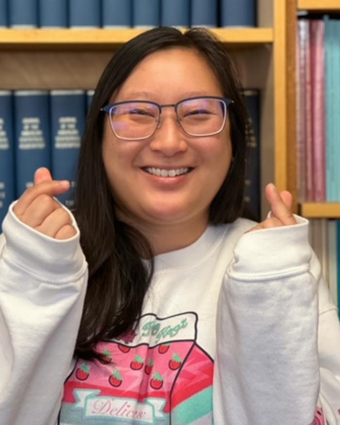 Headshot of a smiling, happy statistics student standing in front of a bookcase