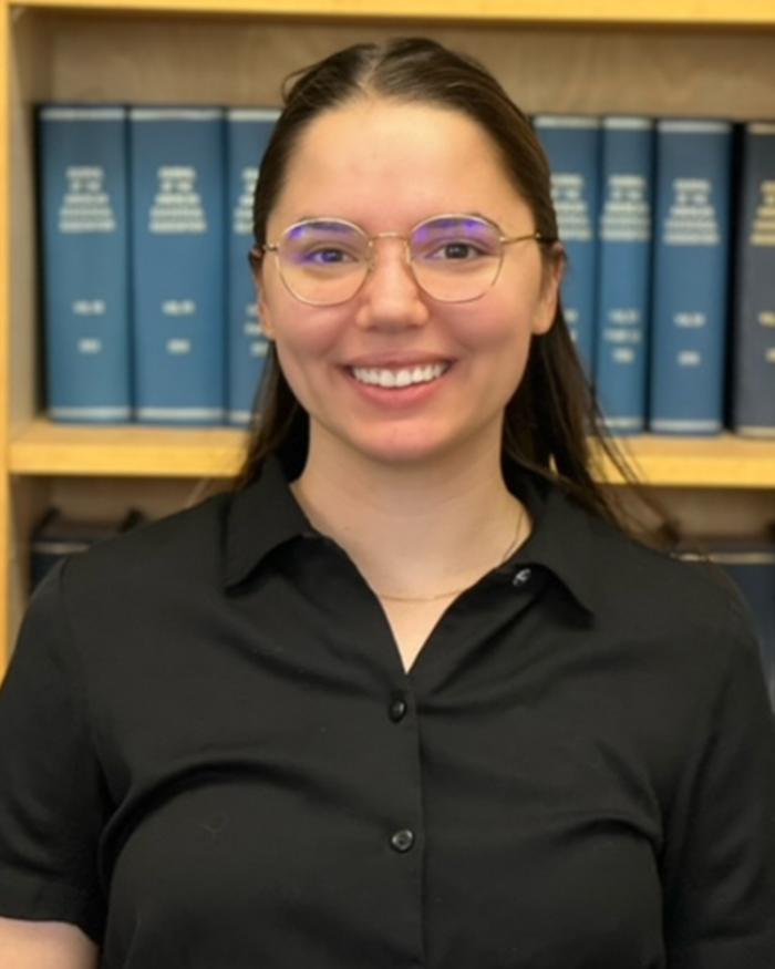 Smiling student standing in front of a bookshelf
