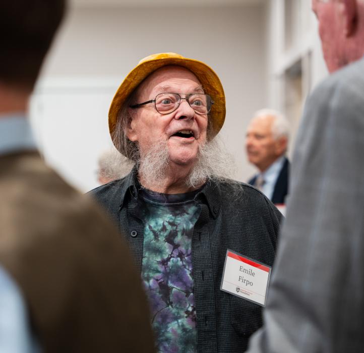 Attendee wearing a yellow hat and patterned shirt speaks with others during the College of Science Alumni Awards reception.